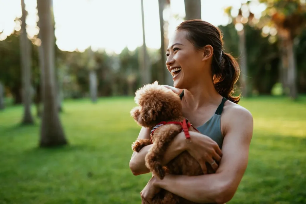 female dog trainer holding dog in park