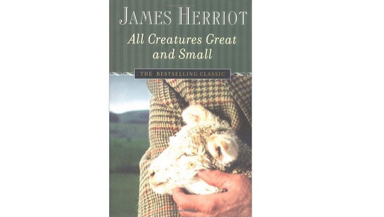 Cover art for All Creatures Great and Small. A man holds a lamb to his chest in the countryside.