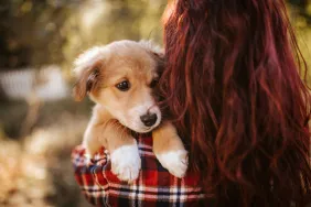 woman hugging and raising puppy