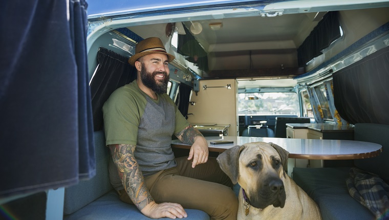 Smiling bearded man with dog in camper van