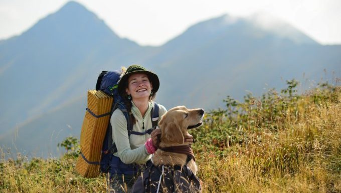 woman hiking in mountains with dog