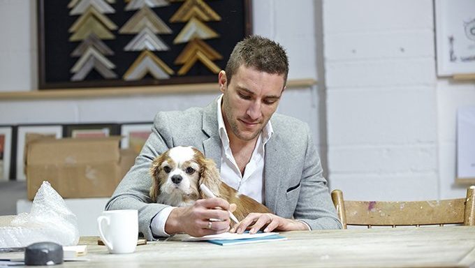 man writes with dog on lap