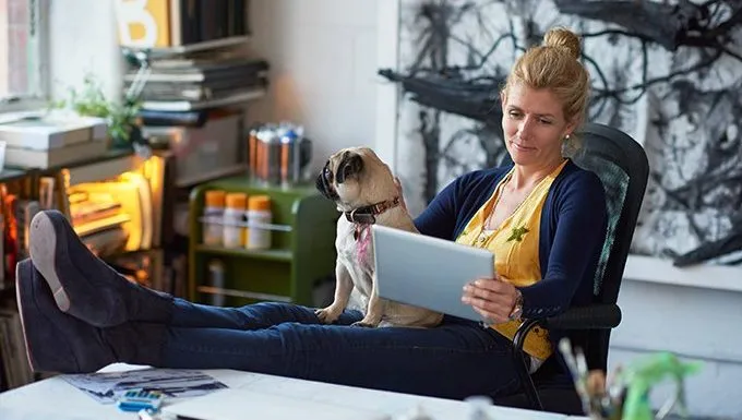 dog sits with woman looking at tablet