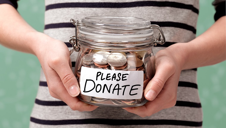 Close up of a girl holding a charity donation jar with coins in.