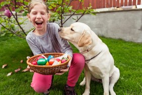 Horizontal image of a 7 years old girl sitting near her golden labrador retriever dog in backyard with a basket full of colorful Easter eggs