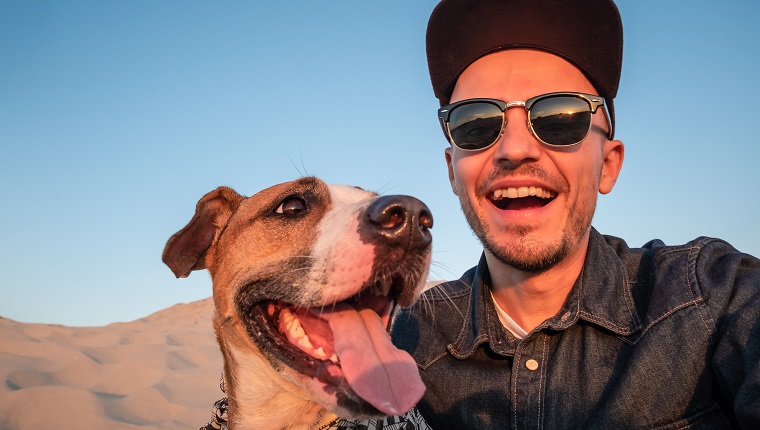 Happy young male person makes self portrait with his dog outdoors