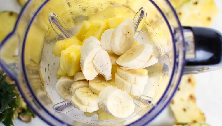 Sliced pineapple and banana in a blender