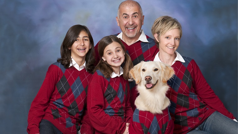 Humorous family portrait with golden retriever dog all in cardigans.