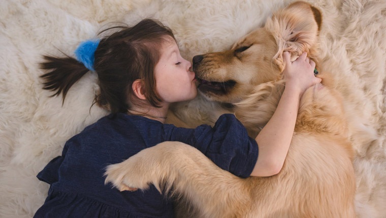 young girl kissing her dog