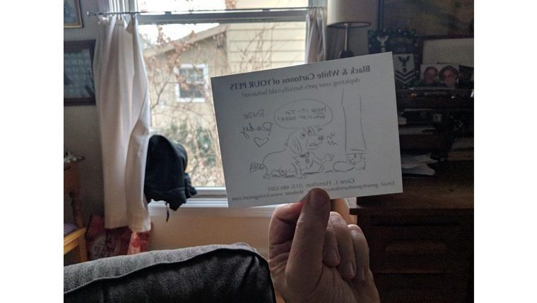 Gene holds a reversed drawing of a dog up to a window