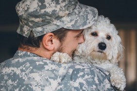 Soldier greeting his cute white dog after long time.