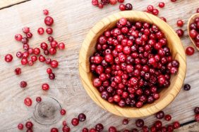 Cranberry in a wooden plate on a wooden background. Cranberries are safe for dogs.