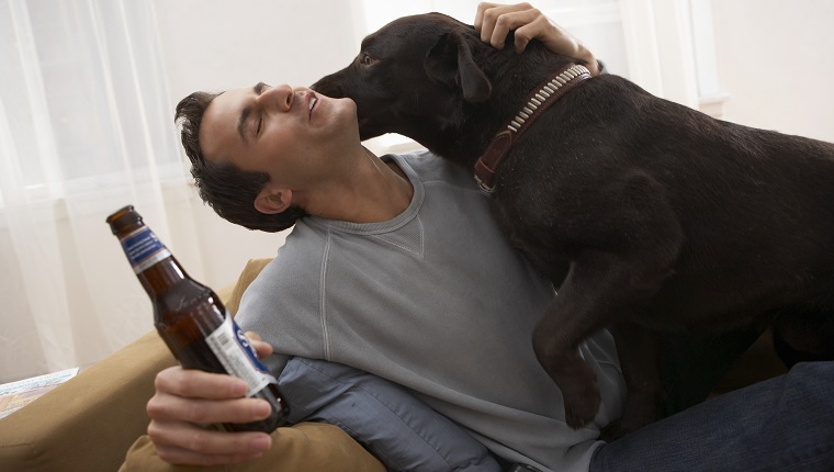 Man holding bottle with dog licking his face
