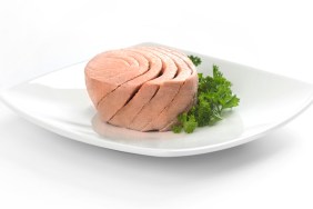 Canned tuna portion served on white dish with parsley.