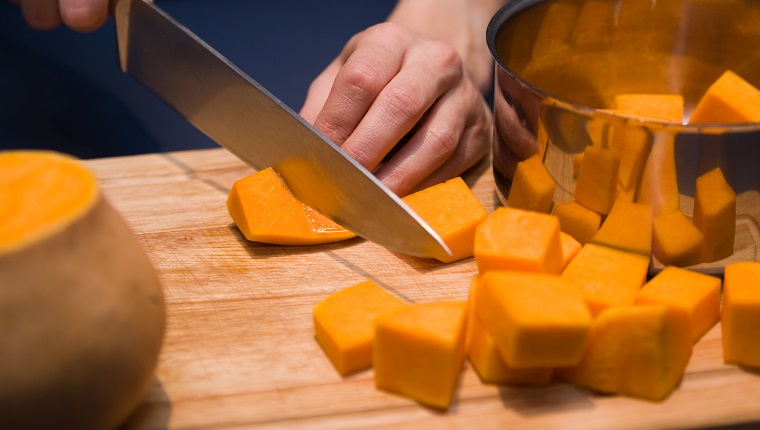 Preparing cubes of pumpkin for cooking. Pumpkin is reflected in the saucepan.