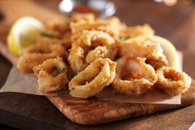 fried calimari rings on wooden tray with dipping sauce shot with selective focus