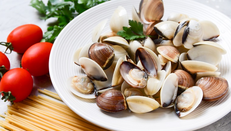 clams, spaghetti, tomatoes and parsley. recipe for traditional seafood Italian pasta Spaghetti alle Vongole. on a gray background. top view, food flat lay