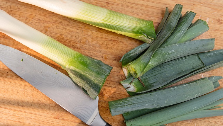 Leek. Chopped leek and kitchen knife on bamboo chopping board. Light effect. High point of view.