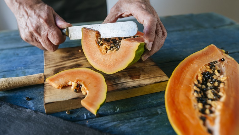 Close-up of man's hands cutting papaya.