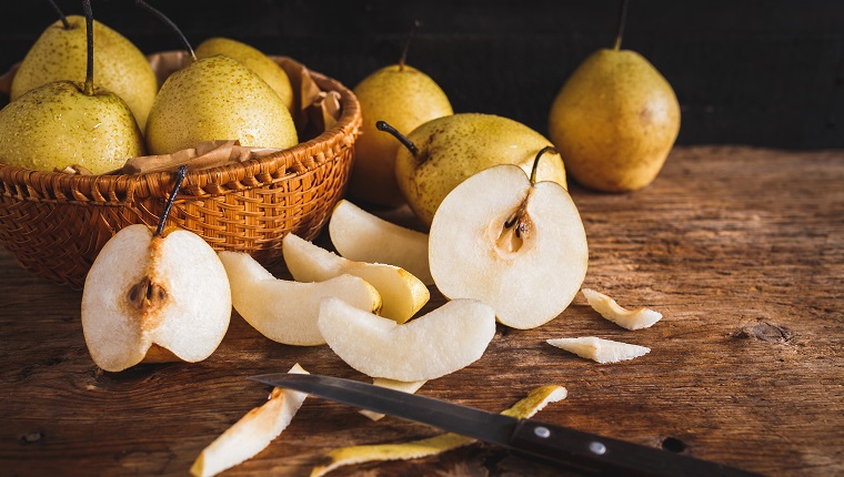 Close-Up Of Pears And Basket With Knife On Cutting Board