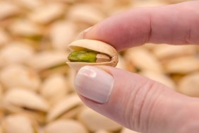 Woman's hand holding tasty pistachio, close up. Healthy eating.