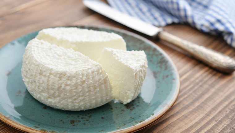 Fresh ricotta on plate on wooden background