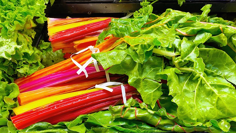 Brightly colored rainbow Swiss chard displayed in the produce department of a market or grocery store.