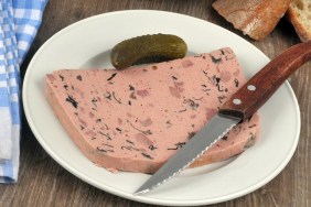 Slice of truffle liver pâté on a plate with a knife in close-up