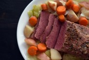 A corned beef brisket on a platter with potatoes, cabbage, and carrots