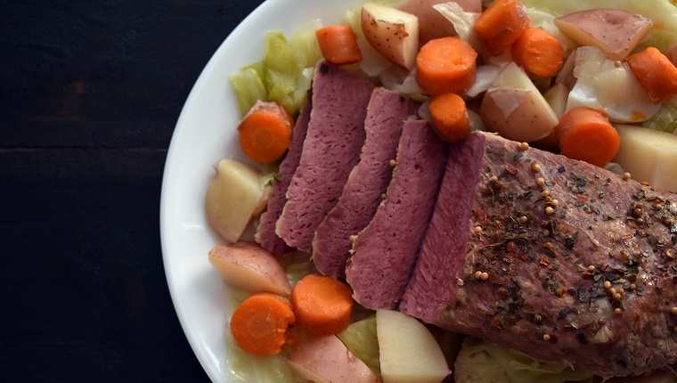 A corned beef brisket on a platter with potatoes, cabbage, and carrots