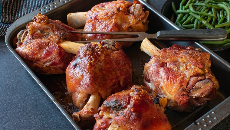 homemade german meal roasted Pork knuckles or pork hock served on a baking tray - ready to eat