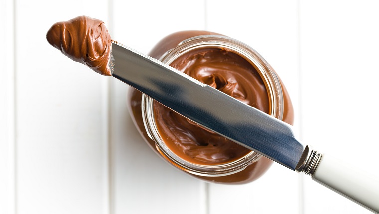chocolate spread with knife on white table