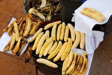 Woman making and selling grilled plantain in Mulago. Uganda.