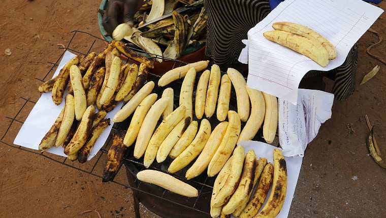 Woman making and selling grilled plantain in Mulago. Uganda.