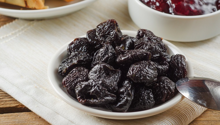 Prunes on small plate with jam from the plums on a wooden table. Dried Plums. Healthy and vegetarian food.