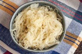 Fermented cabbage in a bowl on a colorful dish towel, top view