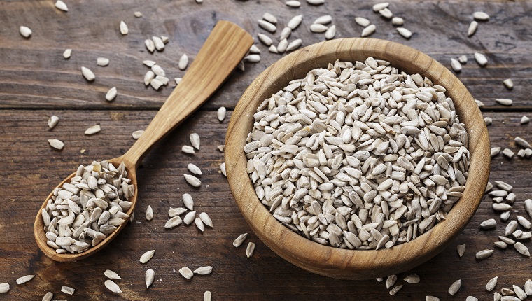 Peeled sunflower seeds on a wooden background in a plate. place for text