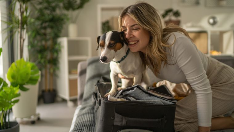 woman packing suitcase with dog leaving your dog at home while you travel