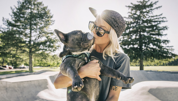 Single woman at skatepark kissing her dog