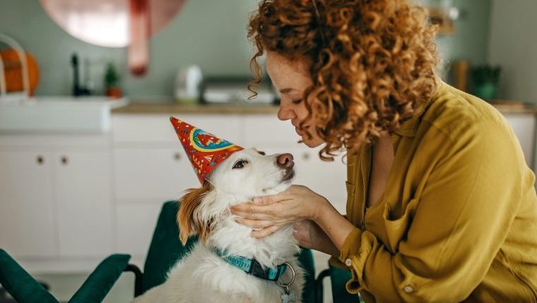 woman hugging dog in birthday hats codependent with dog
