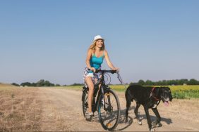 Woman riding bike with dog on leash biking with dogs