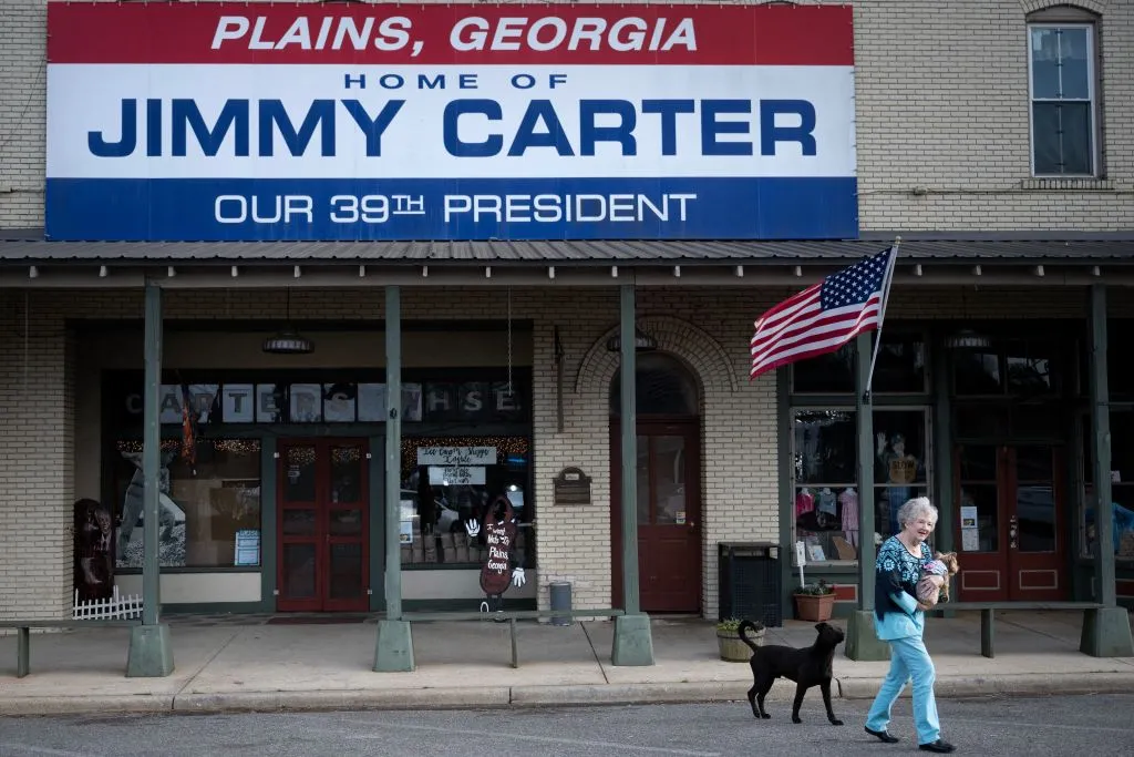 Nell Ariel walks from a shop with her dog Marley on Main Street in Plains, Georgia