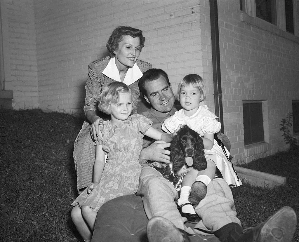 Senator Richard Nixon of California takes time out from the rigors of campaigning to relax with his family at their home in Washington, Sept. 28. It was the GOP Vice Presidential candidate's first visit home since his nationwide broadcast about his expense fund. L to r are: Julie, 4; Mrs. Pat Nixon; Patricia, 6; and Nixon, who holds the family Cocker Spaniel, "Checkers," whom Nixon mentioned in his broadcast.