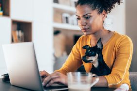 young woman working from home with dog on lap