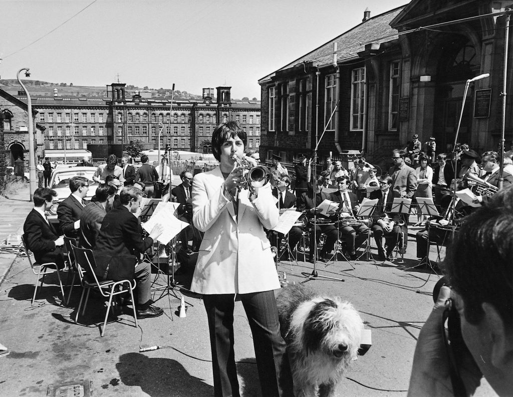 Paul McCartney with The Black Dyke Mills Band, Saltaire, Yorkshire, 30 June 1968. The brass band recorded a version of the McCartney instrumental Thingumybob as one of the first releases on Apple Records. Martha, Paul's Old English Sheepdog, is with him.