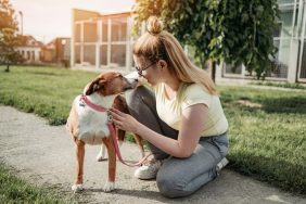 Young adult woman playing with a dog outside of an animal shelter. Dog license fee to increase in Pennsylvania.