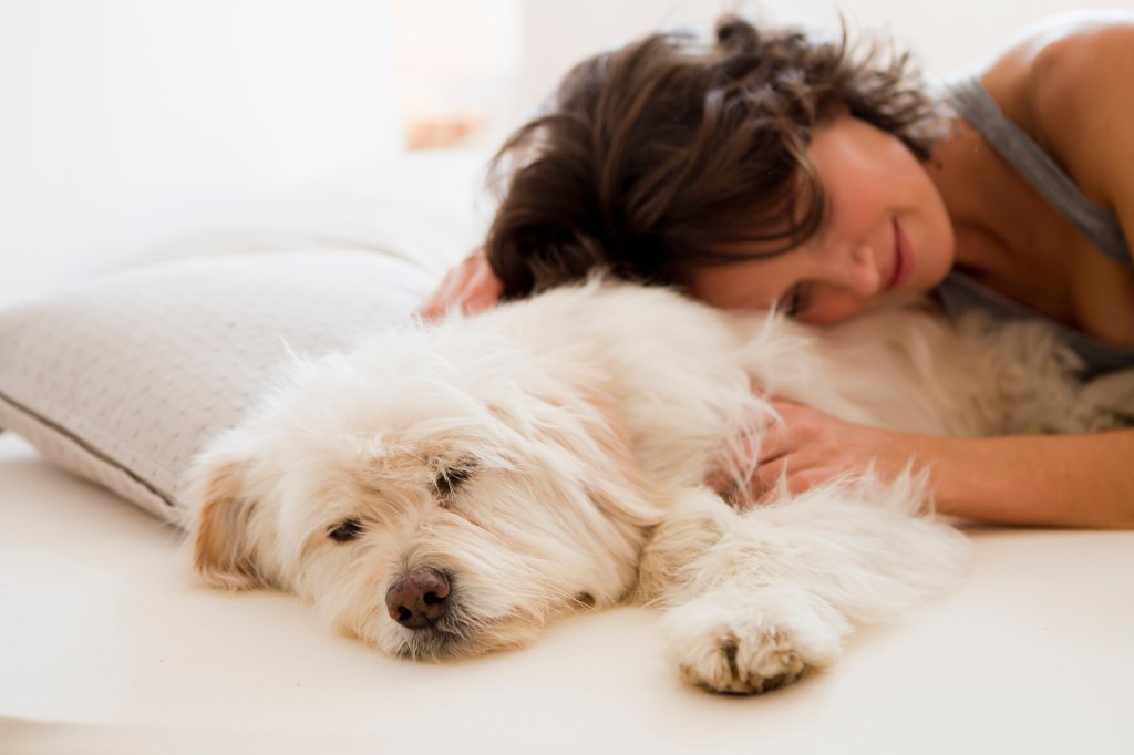 Woman relaxing with her dog in bed.
