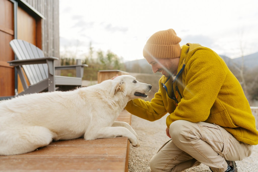 A young man who is smiling while petting his dog.