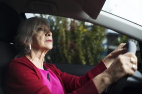 senior woman looking in rearview mirror driving car