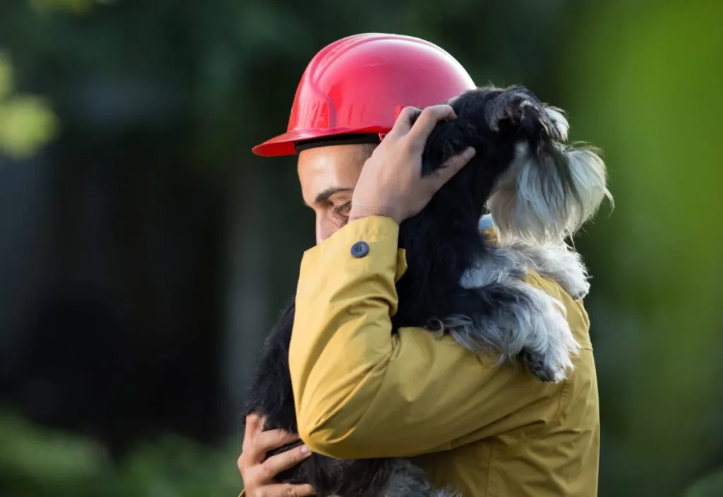 firefighter carrying dog over shoulder